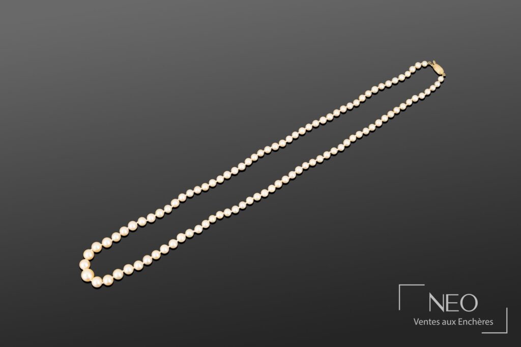 Collier de perles de culture blanches disposées en chute sur fond gris