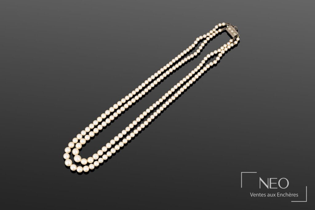 Collier deux rangs de perles de culture blanches disposées en chute sur fond gris