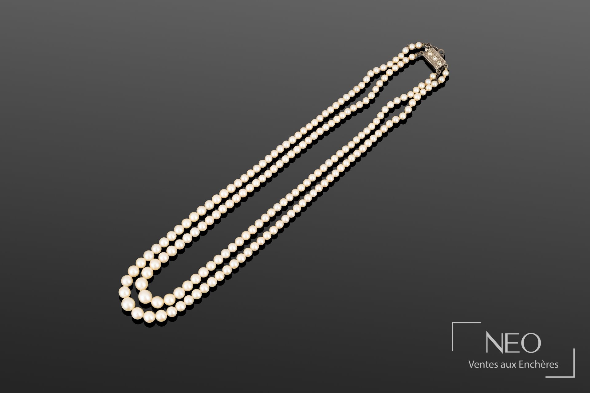 Collier deux rangs de perles de culture blanches disposées en chute sur fond gris