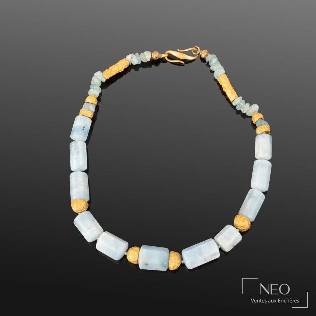 Collier ras-de-cou en métal doré et perles de pierre bleue sur fond sombre