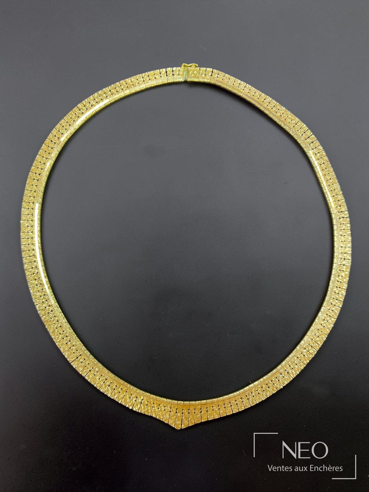 Collier ras-de-cou en or jaune à maille articulée sur fond noir