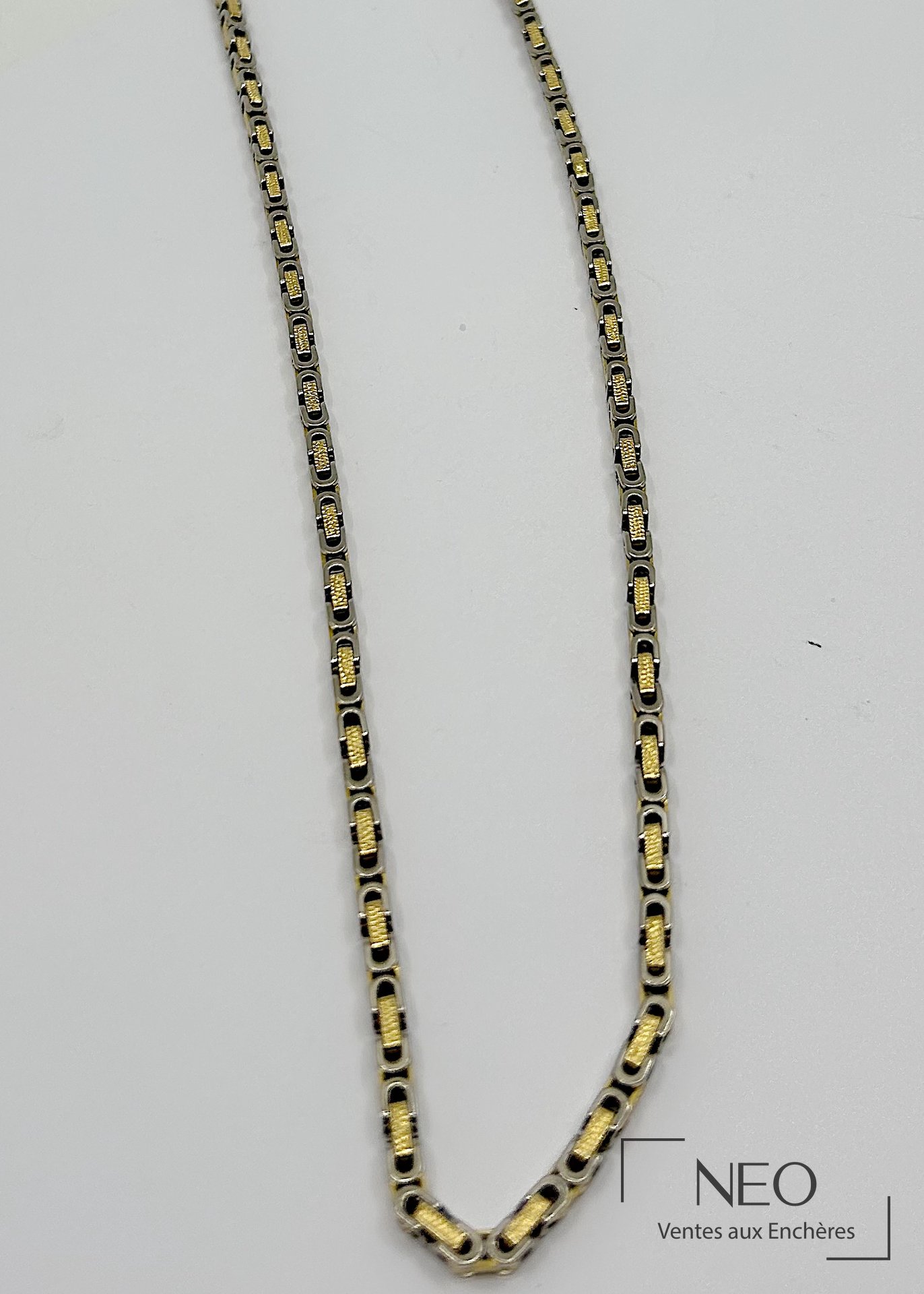 Collier sautoir en or jaune et gris à double maille souple sur fond clair