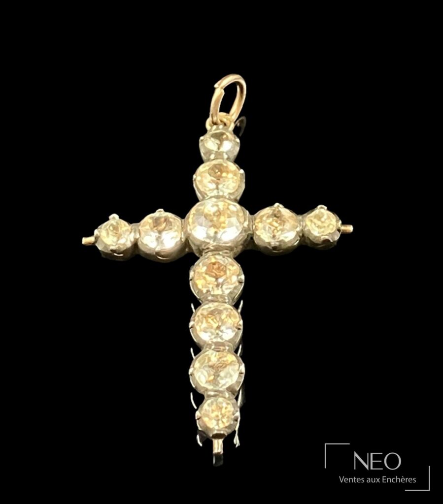 Croix Jeannette d'Arles en argent doré avec bélière en or jaune et strass visibles sur fond noir