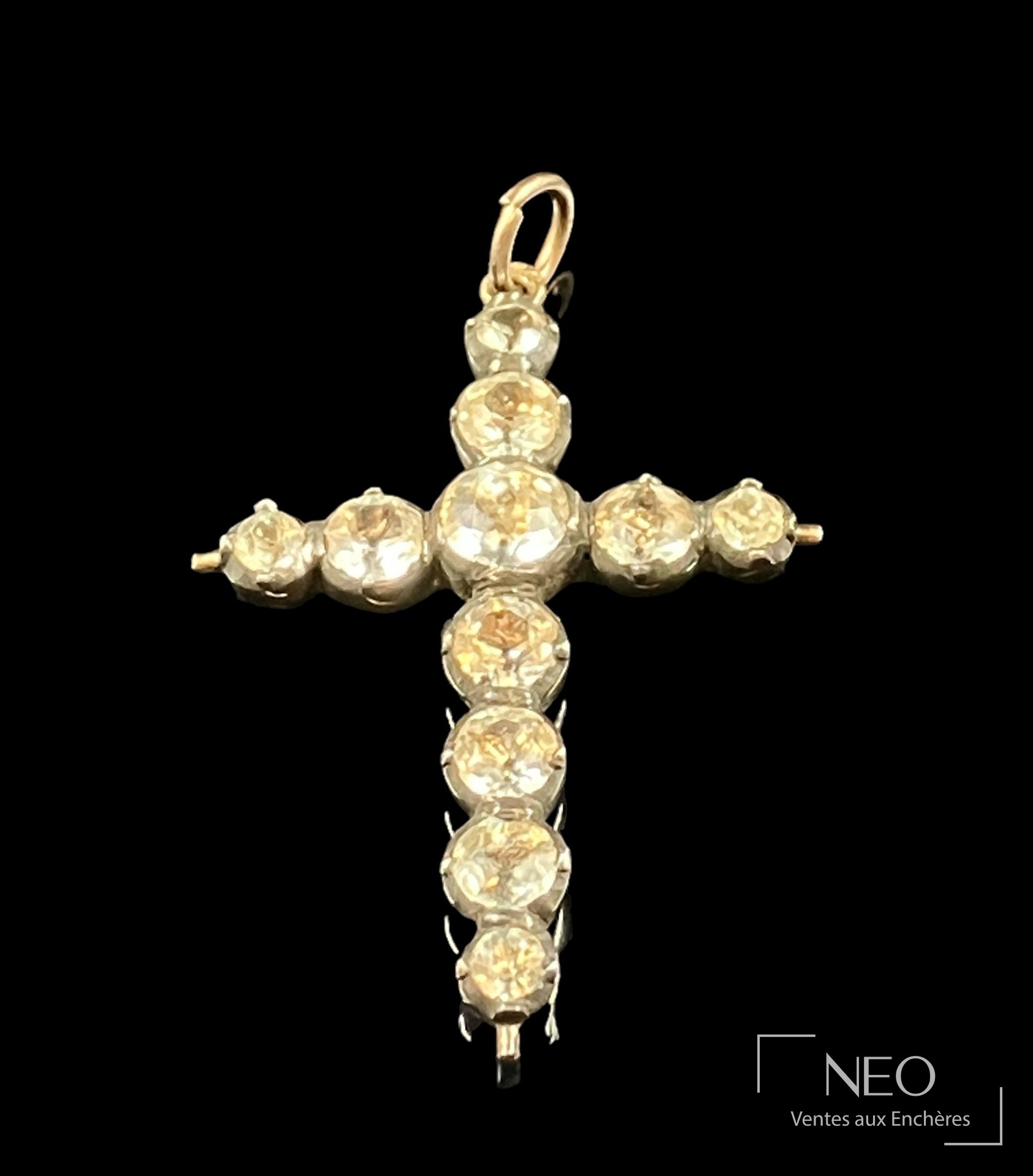 Croix Jeannette d'Arles en argent doré avec bélière en or jaune et strass visibles sur fond noir