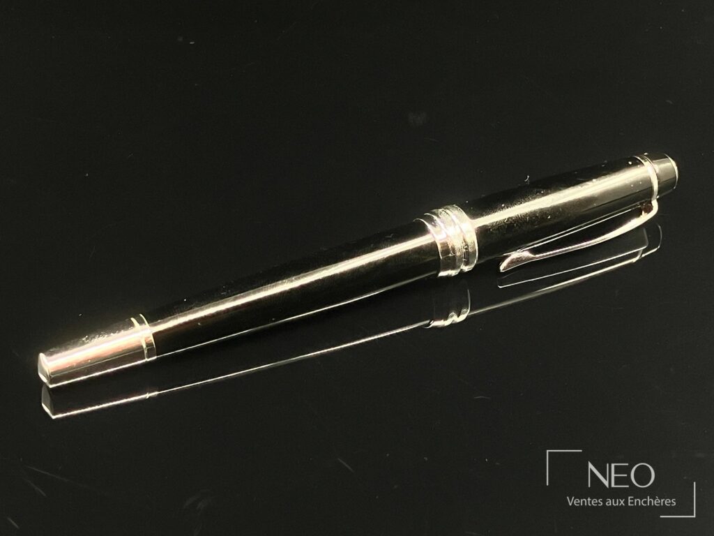 Stylo plume CROSS laqué noir et métal argenté posé de profil sur fond noir