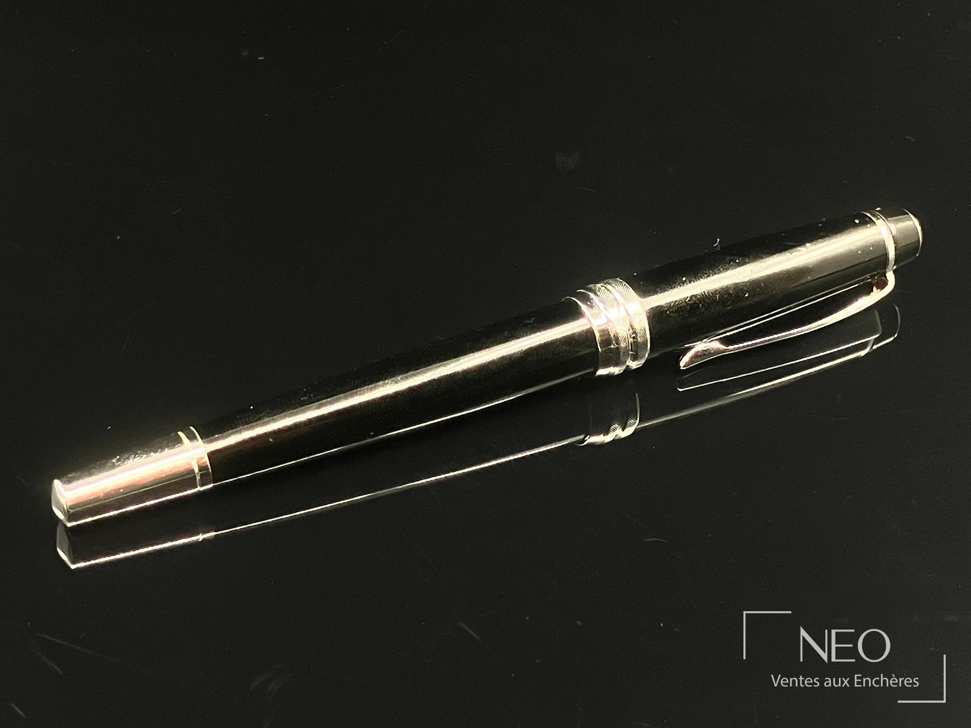 Stylo plume CROSS laqué noir et métal argenté posé de profil sur fond noir