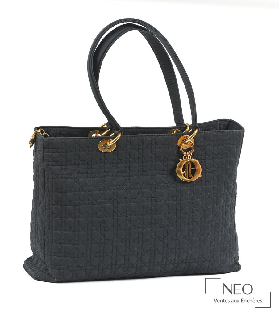 Sac Lady Dior noir en nylon tissé avec anses rigides et breloques dorées.
