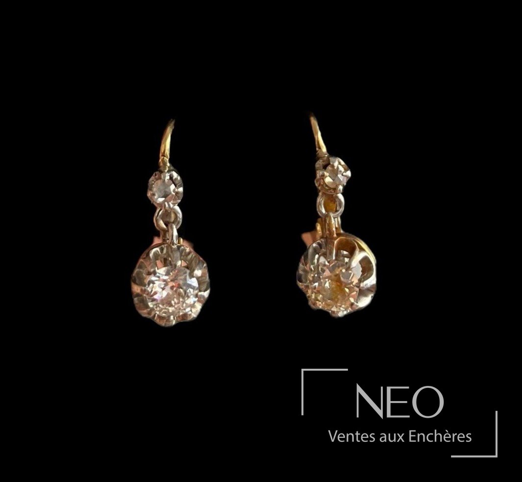 Paire de dormeuses en or jaune et gris avec diamant central sur fond noir