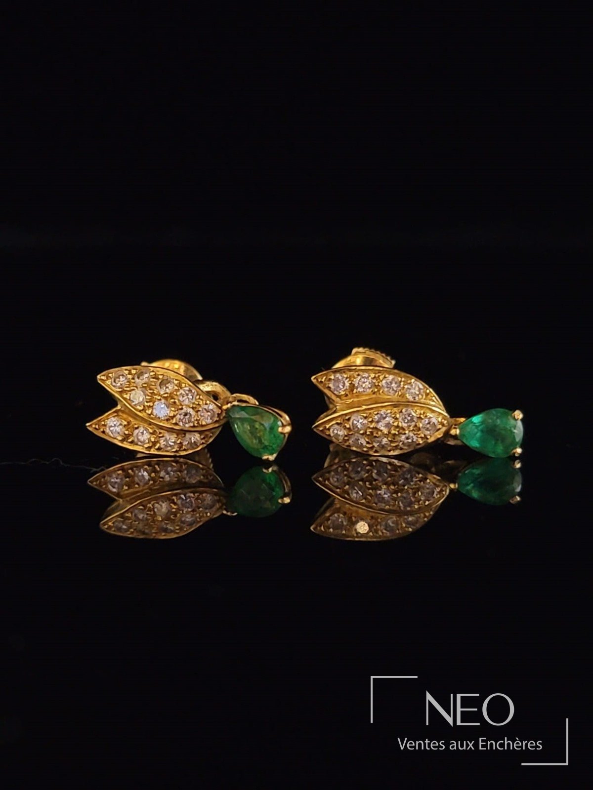 Paire de dormeuses en or jaune avec diamants et émeraudes sur fond noir