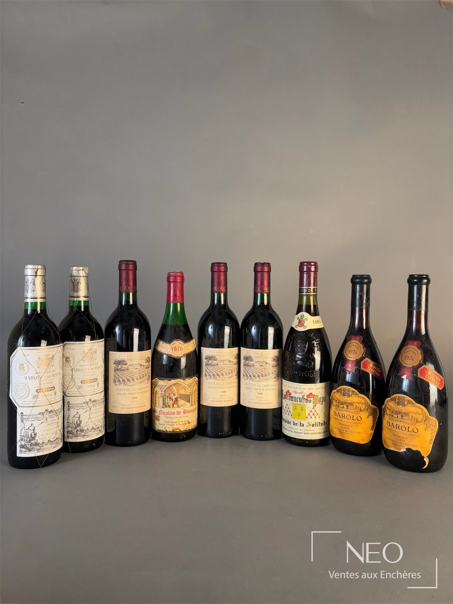 Neuf bouteilles de vins divers alignées sur fond neutre
