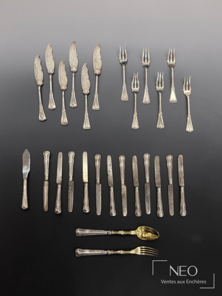 Ensemble de couverts en argent et métal argenté disposés en rangées sur fond noir et gris