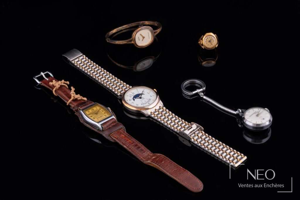 Vue d'ensemble de cinq montres de marques diverses sur fond noir