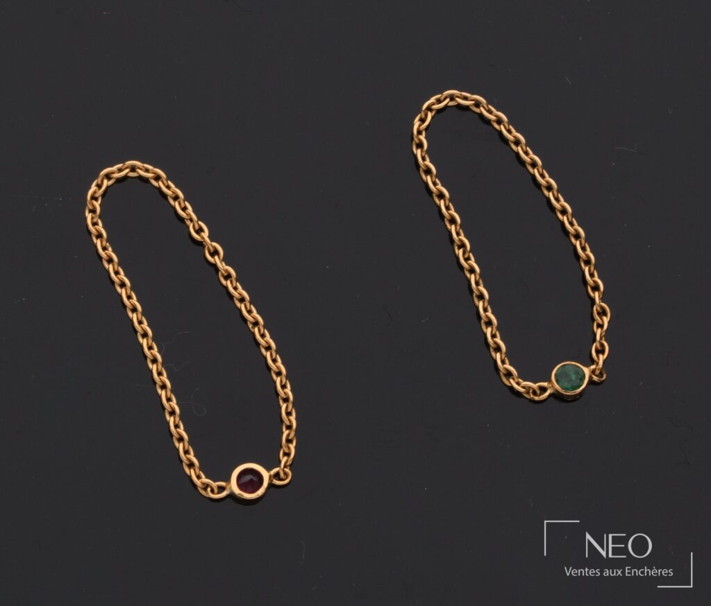 Deux bagues en or jaune 18 carats avec pierre rouge et pierre verte sur fond noir