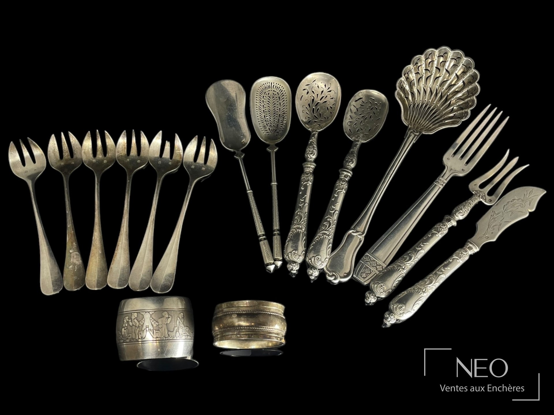 Ensemble de couverts et ronds de serviette en argent présenté sur fond noir