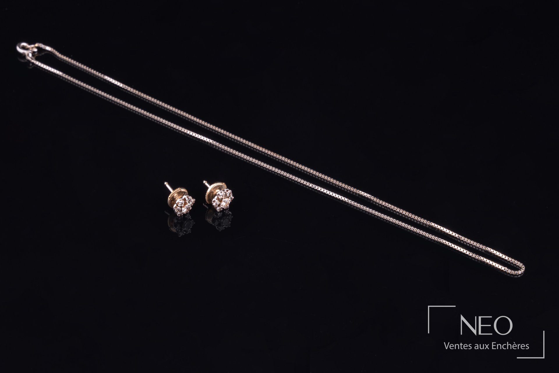 Ensemble chaîne en or gris et puces d’oreille serties de diamants sur fond noir
