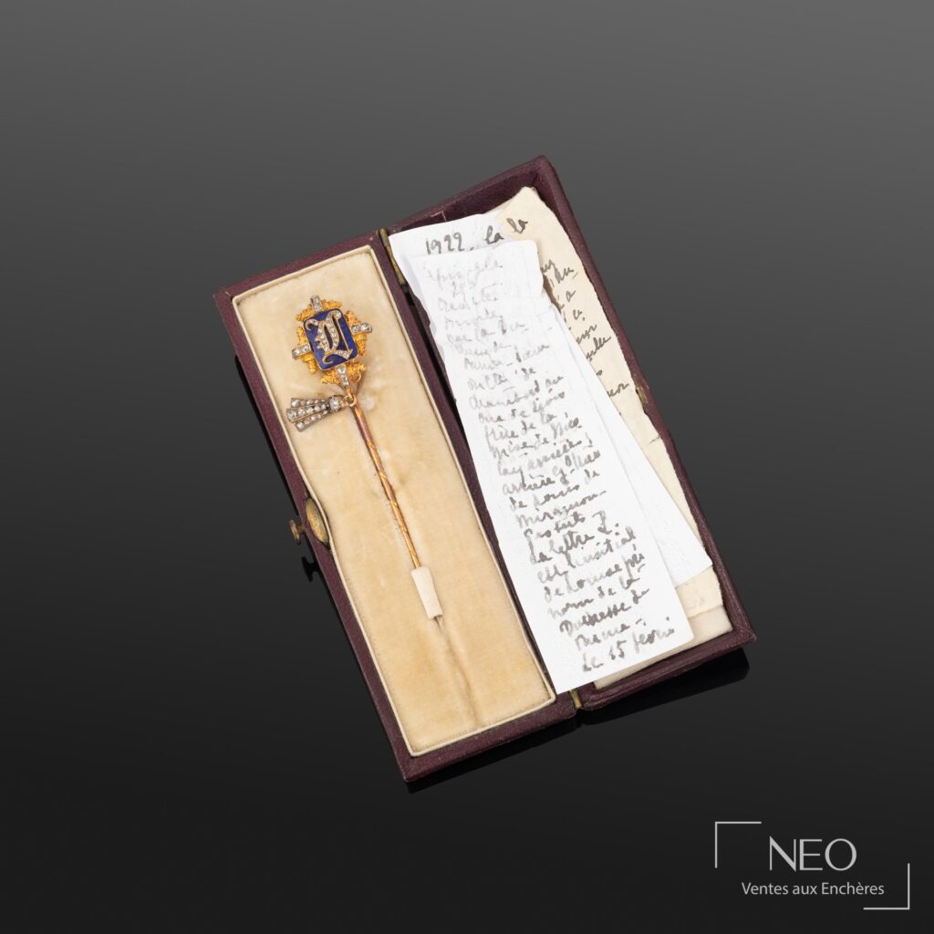 Épingle de cravate dans son écrin avec manuscrits et note ancienne visibles