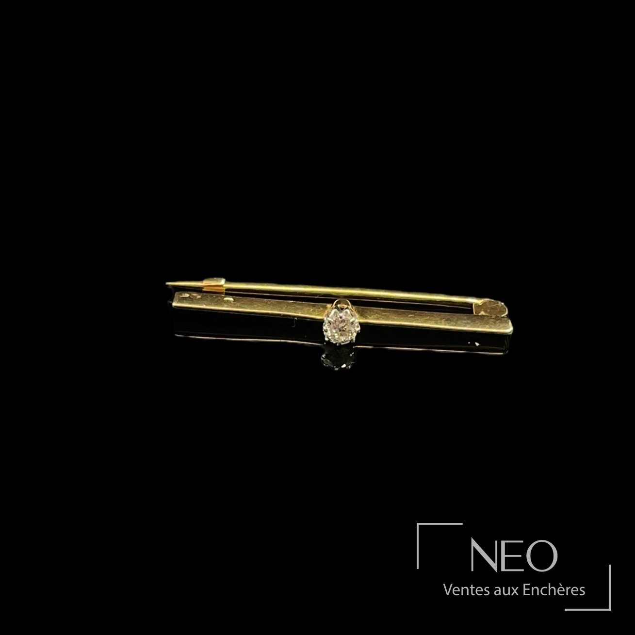 Petite épingle en or jaune et platine avec diamant central sur fond noir