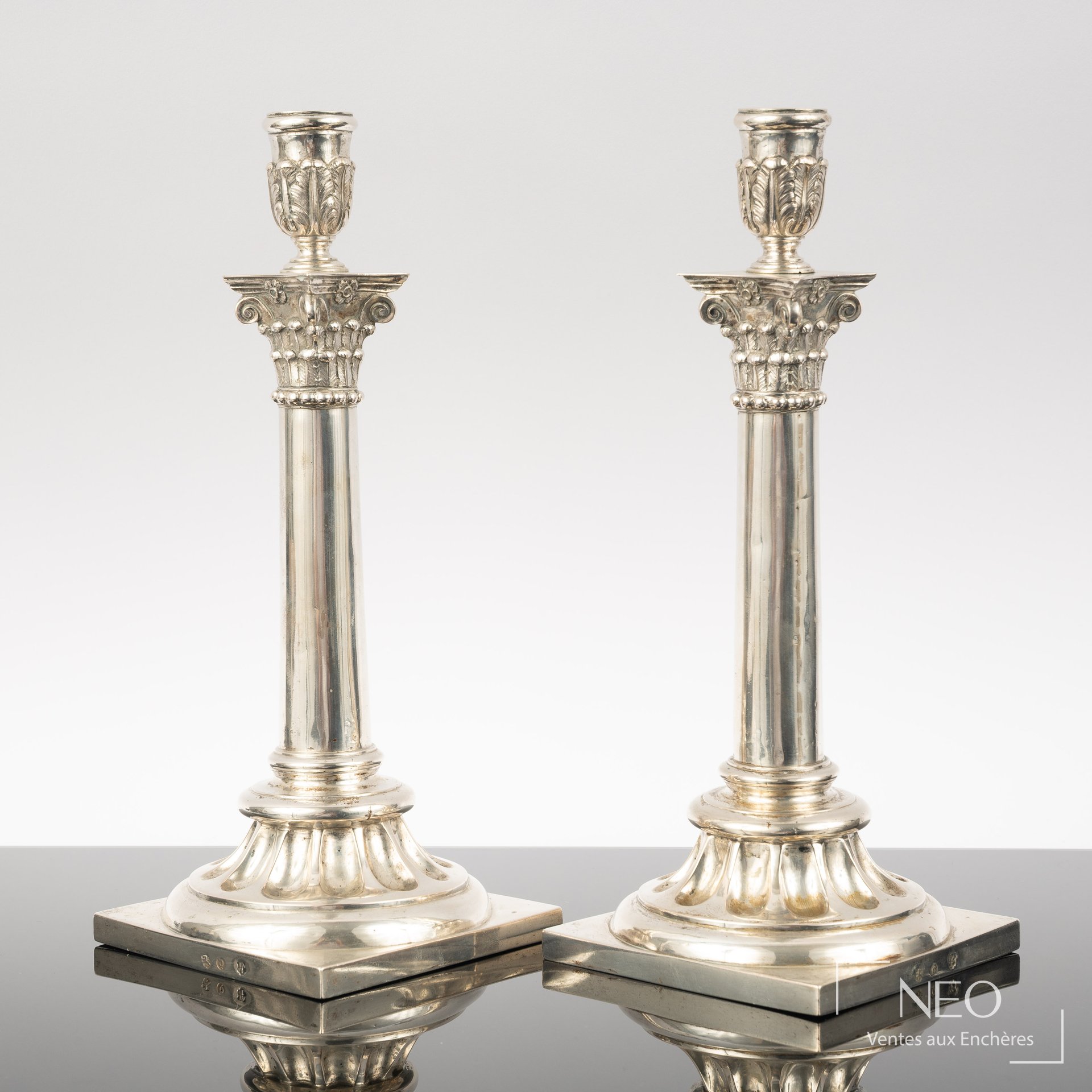 Paire de flambeaux en argent à bases carrées et fûts à décor corinthien