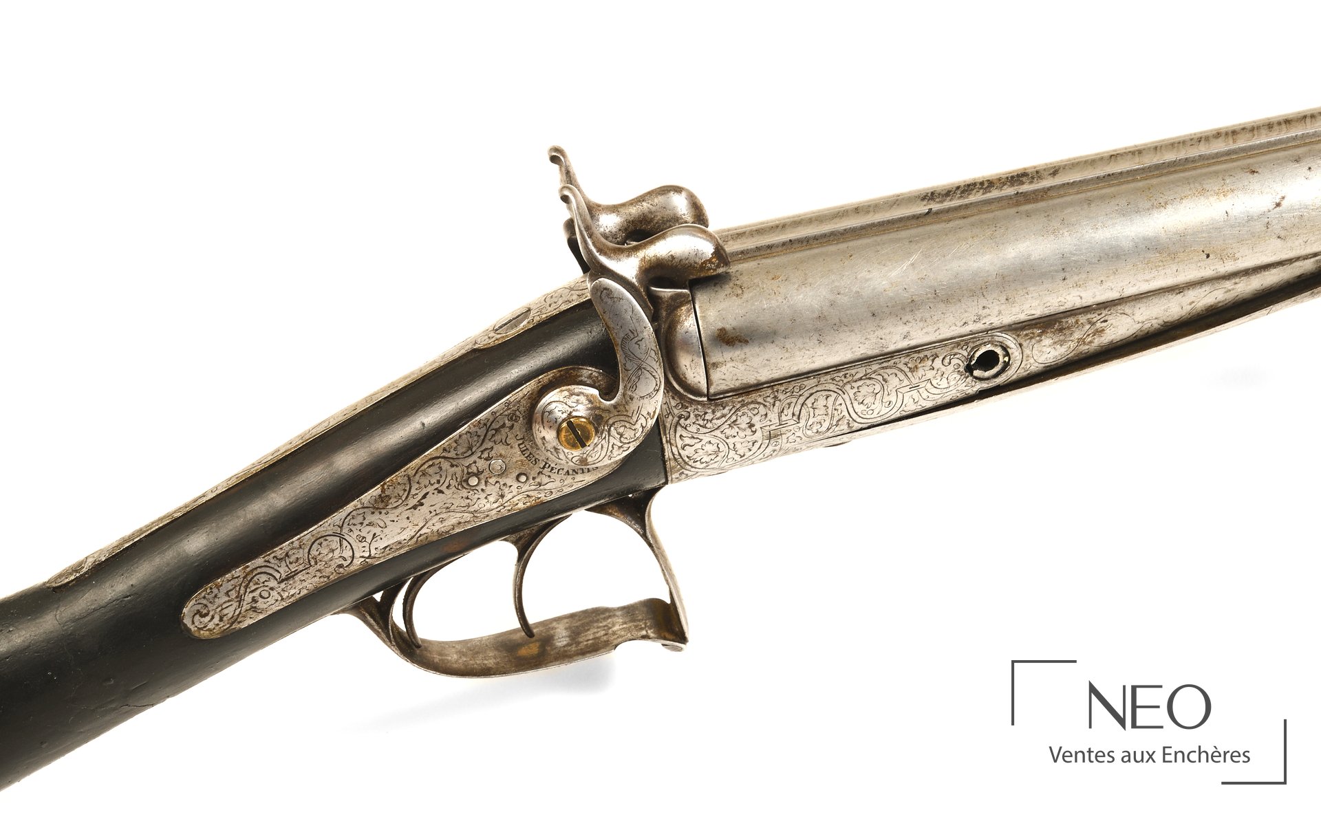 Gros plan sur la bascule et la platine gravée d'un fusil de chasse à broche.