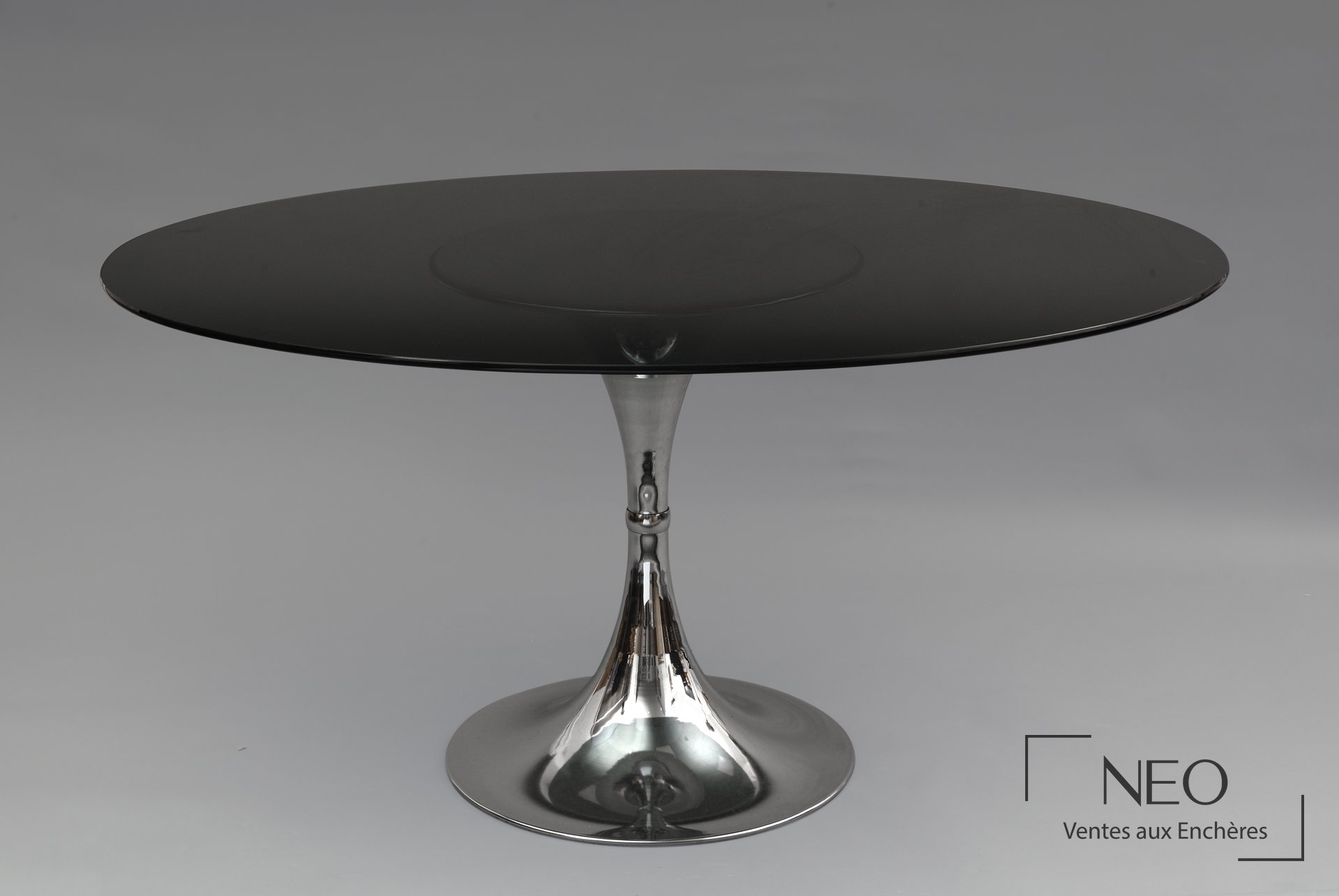 Table ovale en verre fumé avec piètement central tulipe en métal chromé