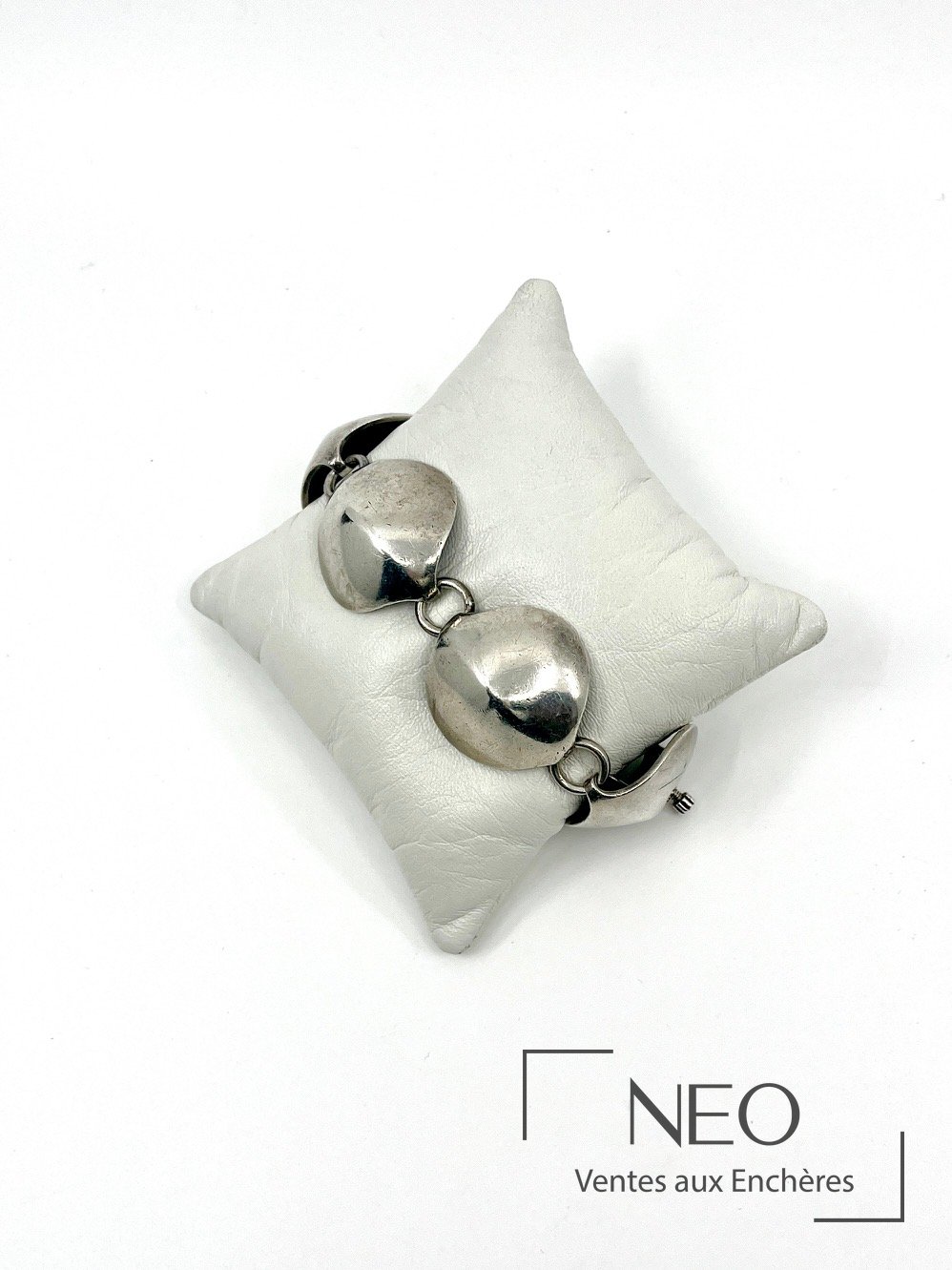 Bracelet en argent à cinq maillons stylisés sur coussin blanc