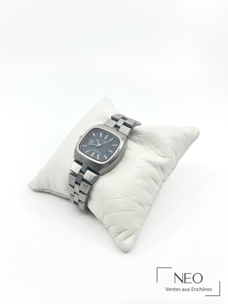 Montre bracelet GIRARD-PEREGAUX en acier posée de biais sur coussin blanc