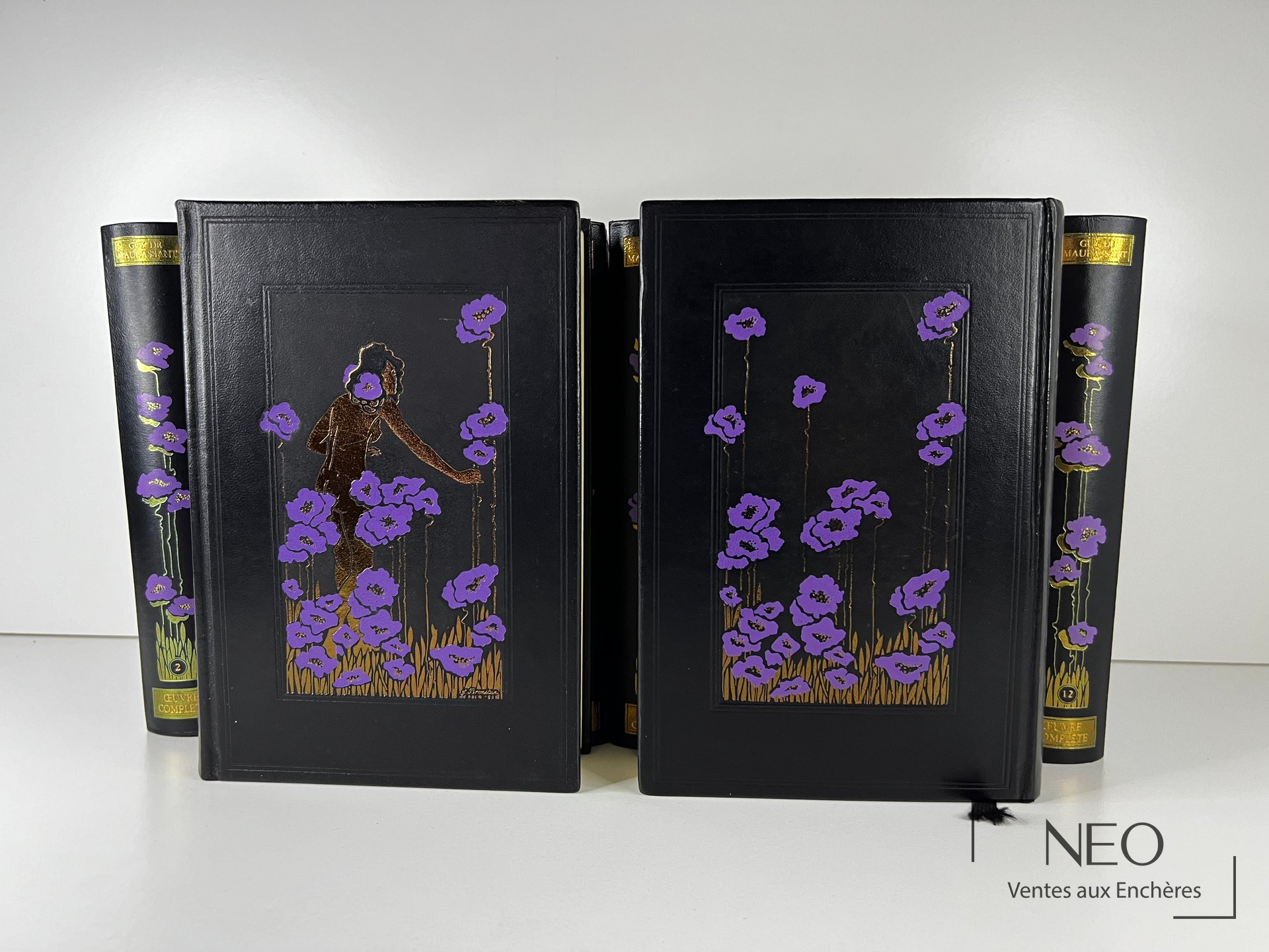 Ensemble de douze volumes noirs à décor floral violet et doré de Guy de Maupassant