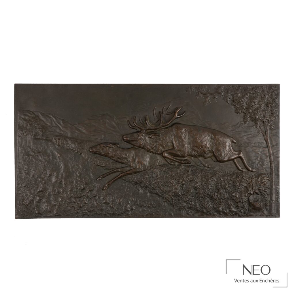 Bas-relief en bronze patiné représentant un cerf et une biche en course dans un paysage de montagne