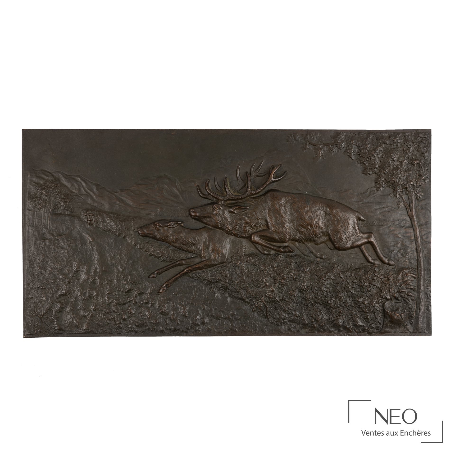 Bas-relief en bronze représentant un cerf et une biche en mouvement dans un paysage boisé