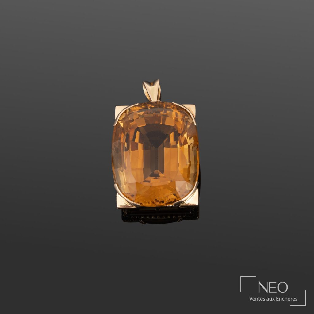 Pendentif serti d'une grande pierre facettée orange sur fond gris