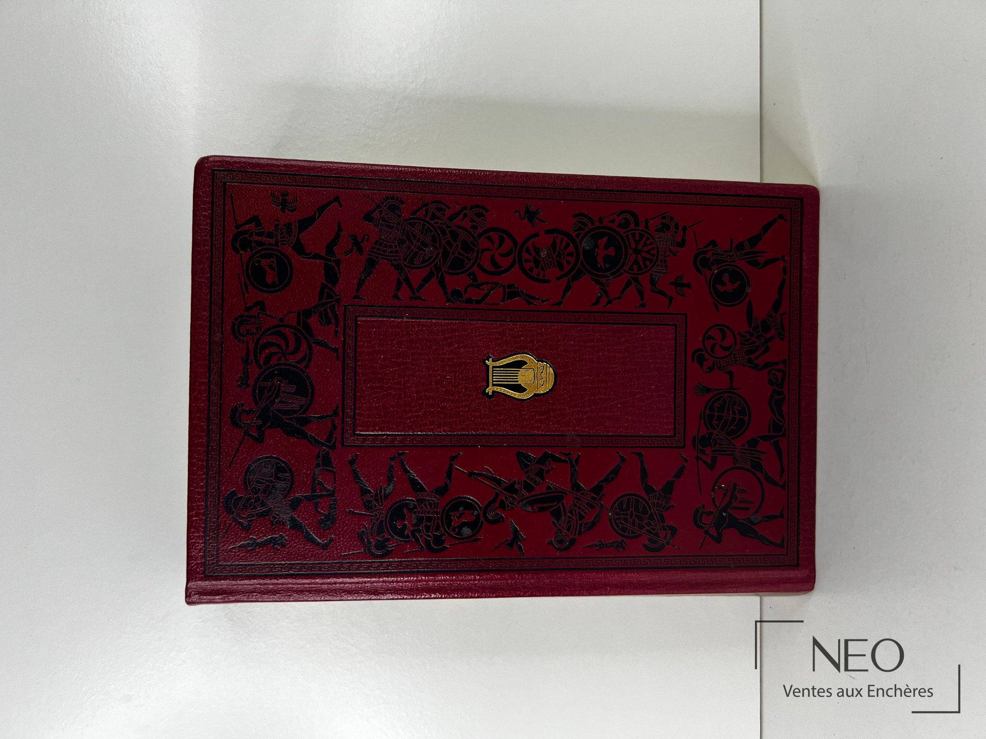 Reliure rouge décorée d une scène guerrière noire avec cartouche central doré