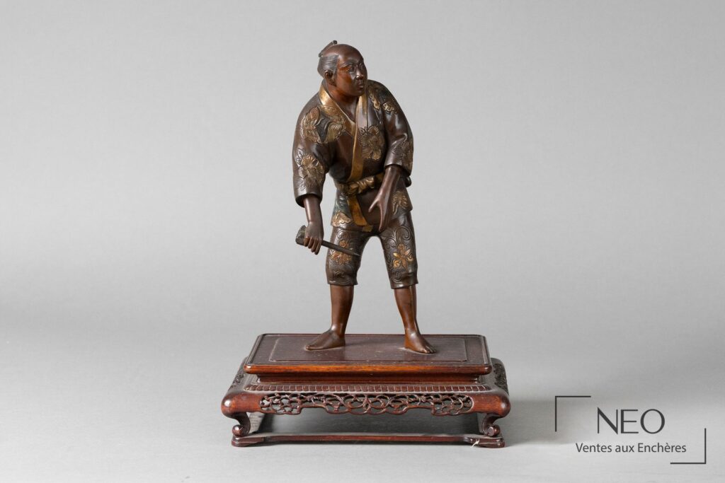 Okimono japonais en bronze représentant un homme au pic sur socle ajouré