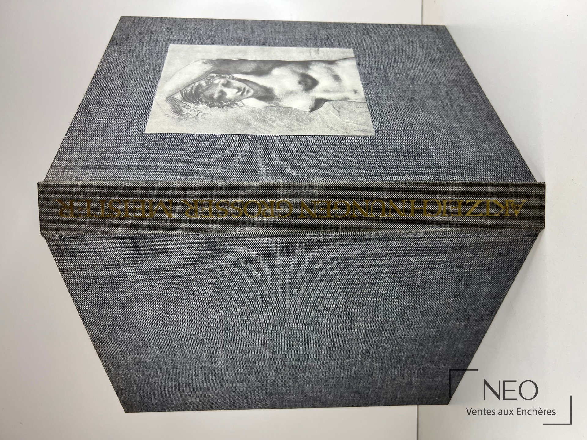 Couverture rigide grise d’un livre in-folio avec illustration centrale en noir et blanc