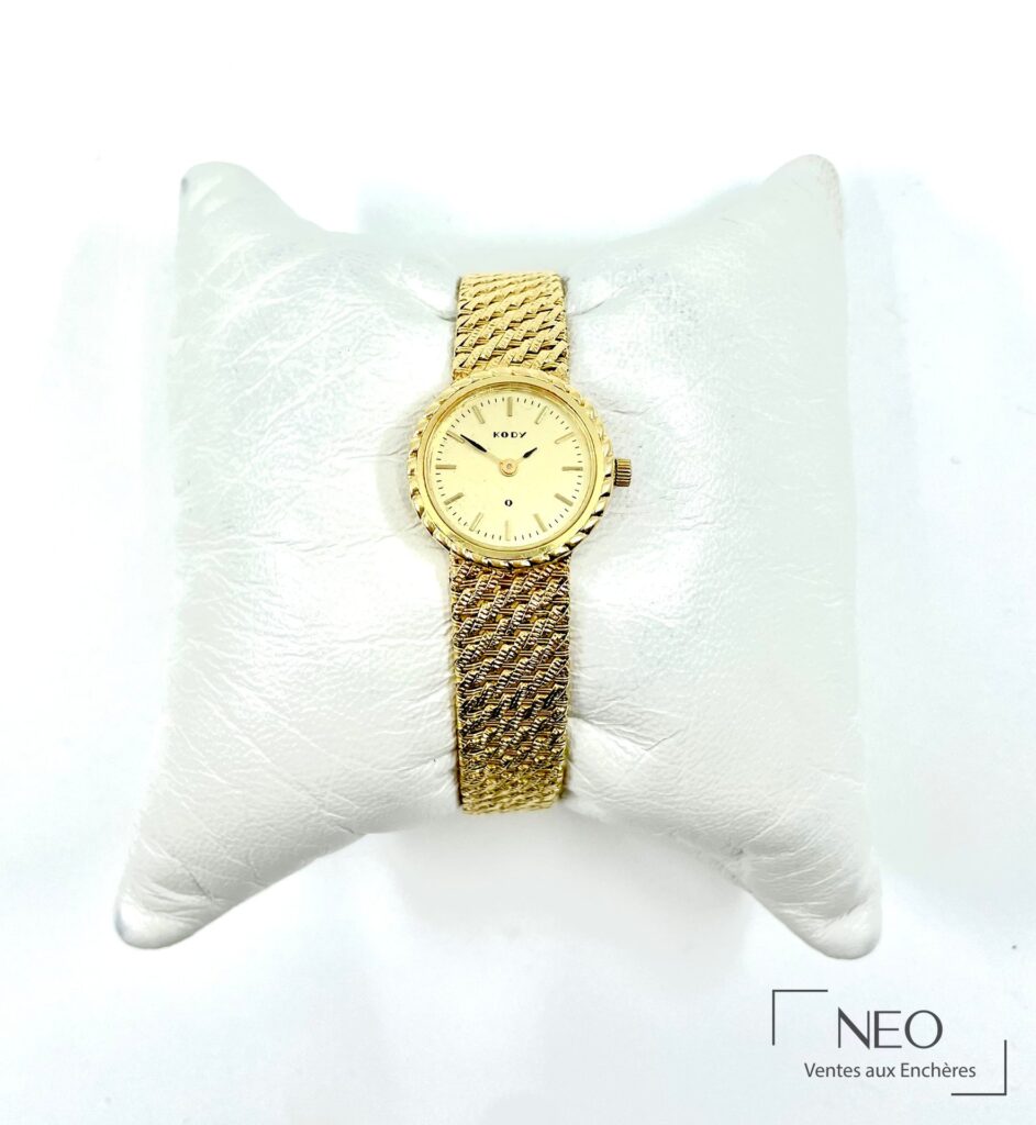Montre bracelet KODY en or jaune portée sur support blanc