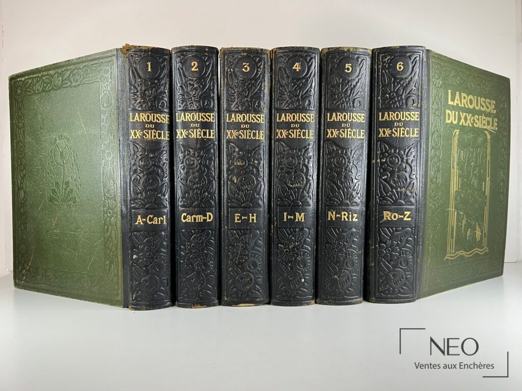 Les six volumes du Larousse du XXe Siècle en reliure verte et noire sont alignés de face.