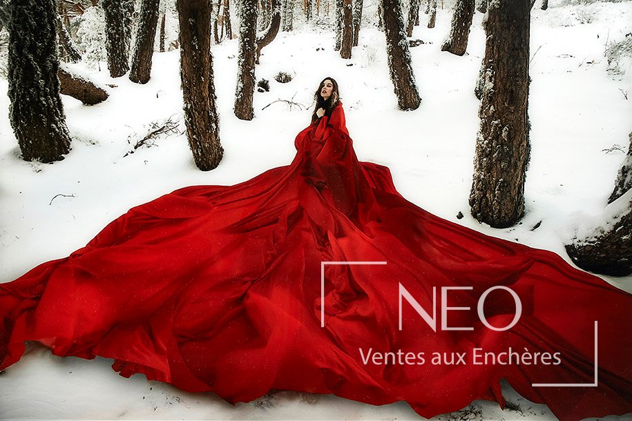 Tirage couleur montrant une femme drapée de rouge dans un paysage enneigé.