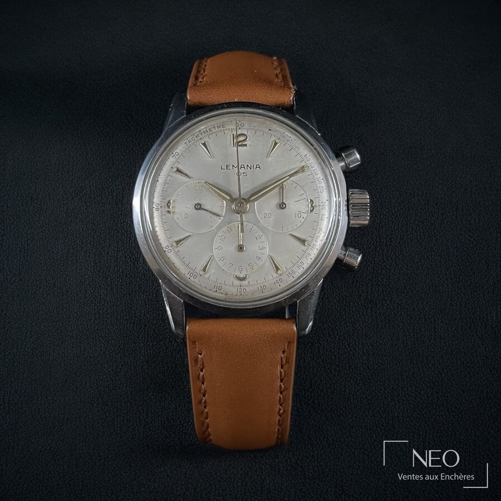 Montre chronographe Lemania 105 en acier avec cadran argenté et bracelet brun.