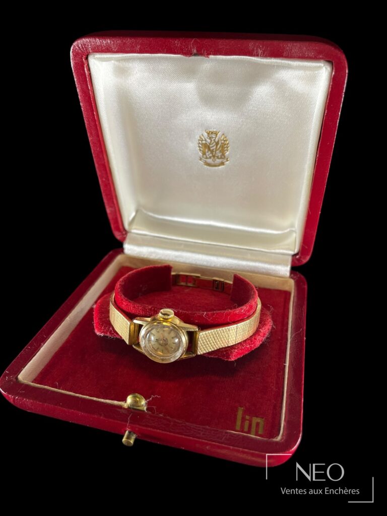 Montre-bracelet LIP en or jaune présentée dans son écrin rouge.