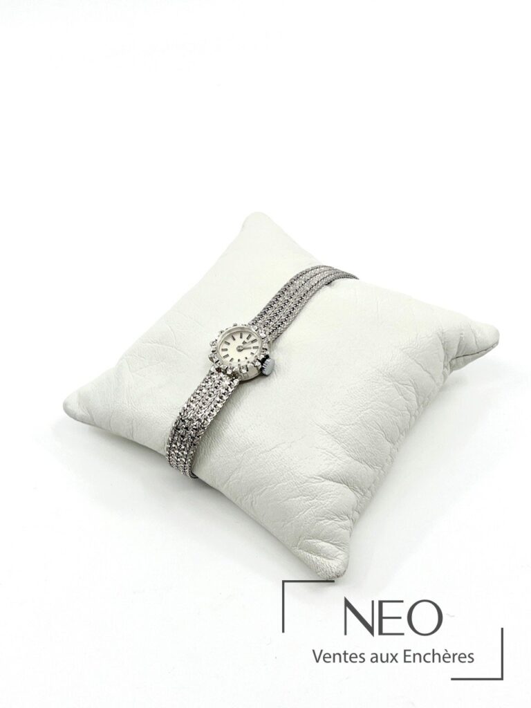 Montre LIP de dame en or gris sur coussin blanc