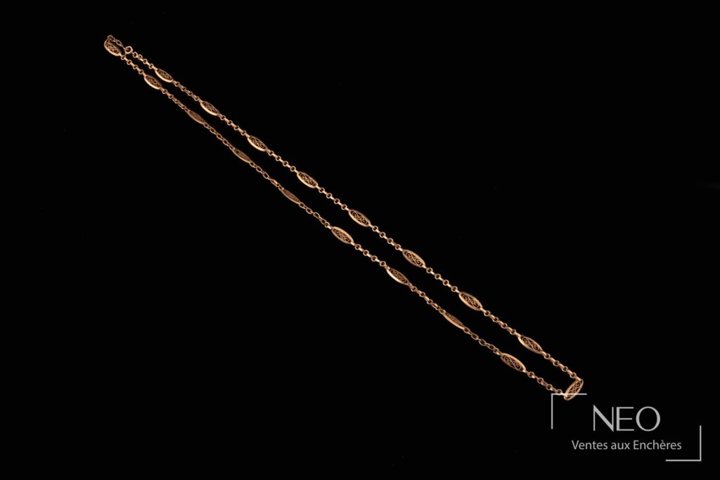 Long collier en or jaune à maille filigrane sur fond noir