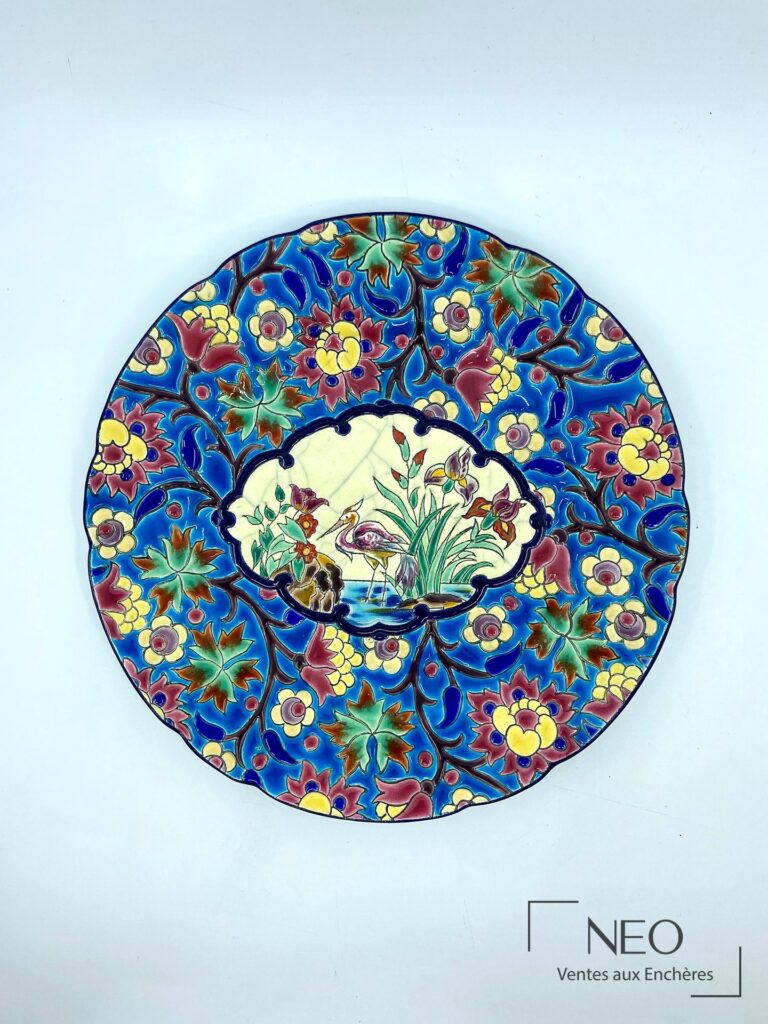 Assiette Longwy en émaux polychromes à décor floral et médaillon central à la grue