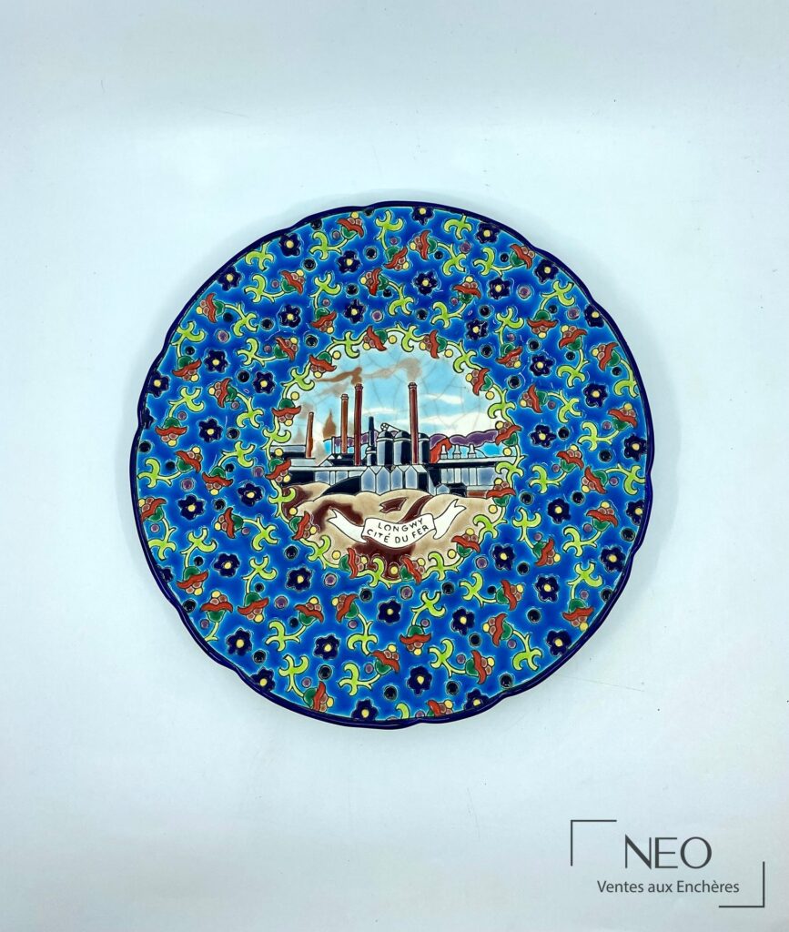 Assiette Longwy en émaux polychromes à décor floral et médaillon central industriel