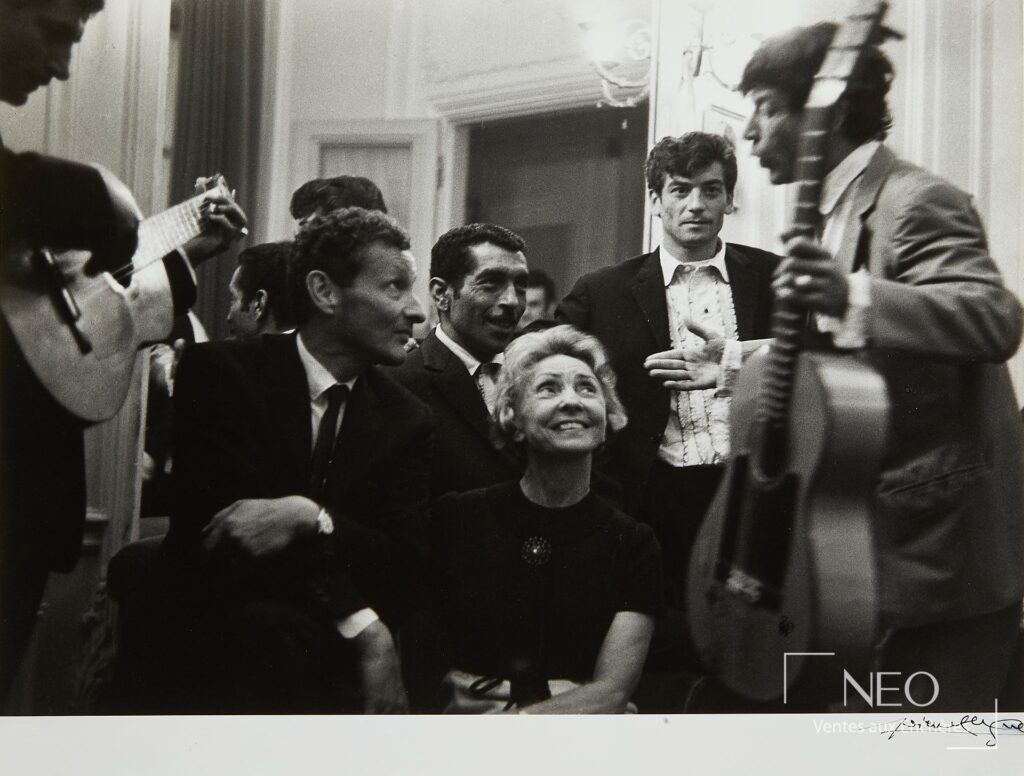 Photographie noir et blanc montrant plusieurs musiciens et un couple au foyer d'un théâtre.