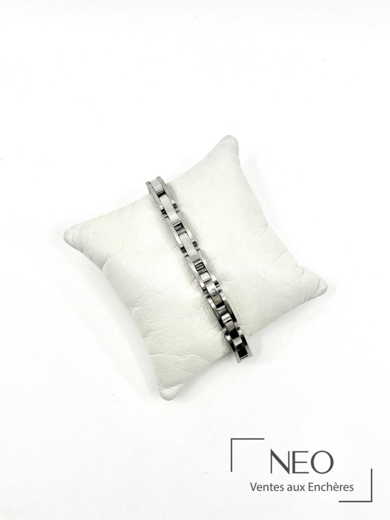 Bracelet en acier posé sur un coussin blanc