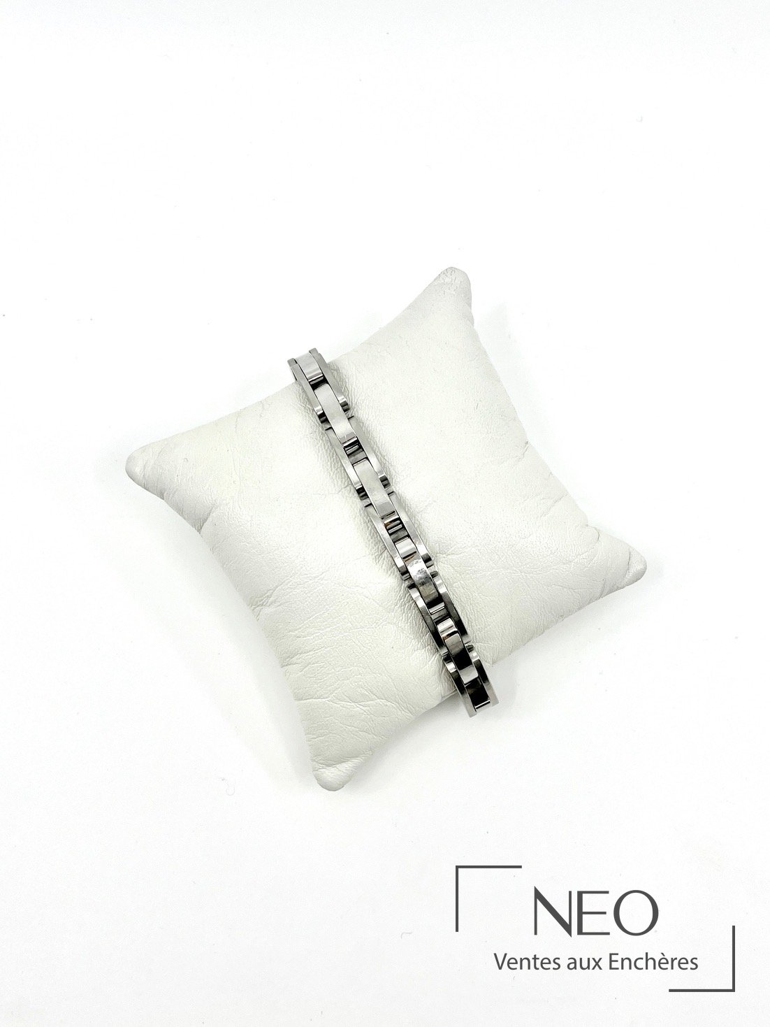 Bracelet en acier posé sur un coussin blanc