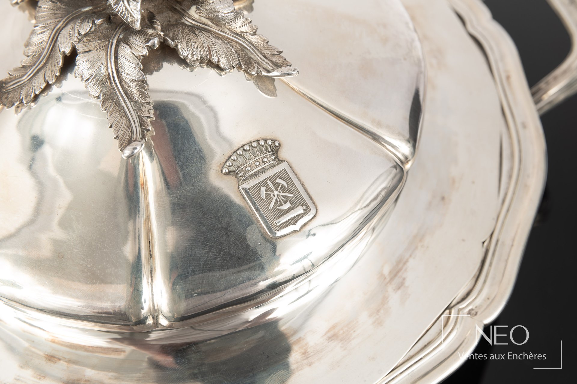 Gros plan d’un couvercle en argent Odiot avec blason couronné et prise en forme de pomme de pin