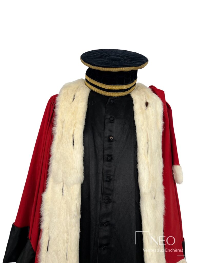 Mannequin de magistrat vêtu d'une robe rouge à doublure claire et toque en velours noir.