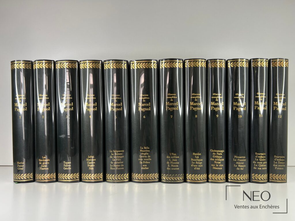 Douze volumes noirs et dorés des Œuvres complètes de Marcel Pagnol alignés de face