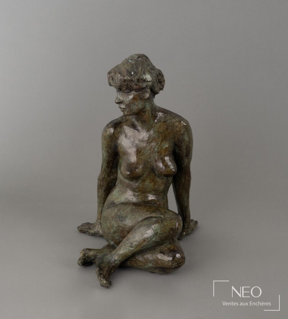Sculpture en bronze à patine verte représentant une figure féminine assise de face.