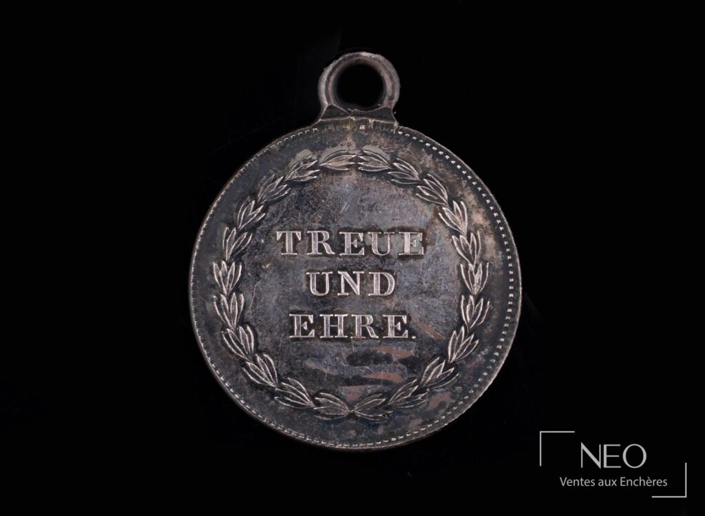 Revers d’une médaille suisse en argent avec la devise TREUE UND EHRE dans une couronne de feuillage.